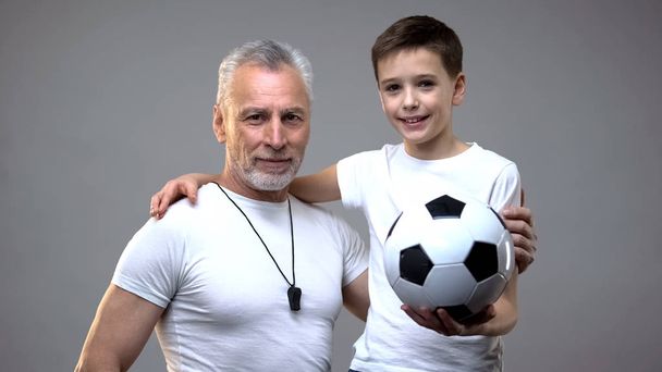Senior football coach smiling hugging teen boy, active healthy lifestyle, sports - Photo, Image