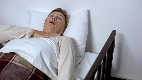 Retired woman patient lying in sickbed feeling asthma attack and asking for help - Φωτογραφία, εικόνα