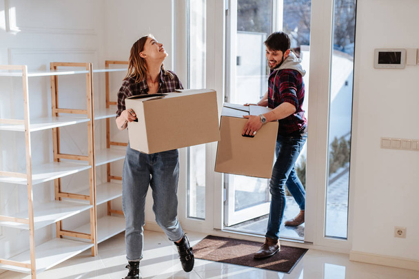Couple portant des boîtes dans une nouvelle maison le jour du déménagement
 - Photo, image