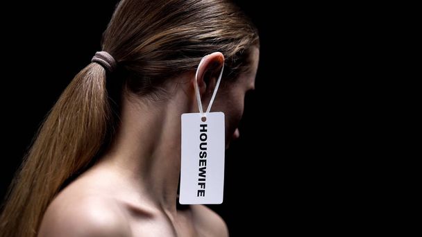 Lady with housewife label on ear against dark background, place of women, sexism - Fotó, kép