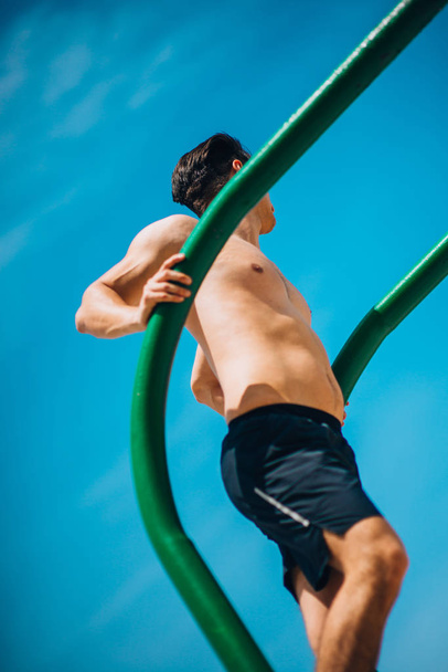Fitness man doet dips bij outdoor gym workout - Foto, afbeelding