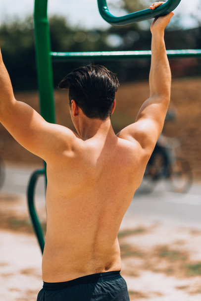 Fit man working out at the beach on chin up bar - Photo, Image