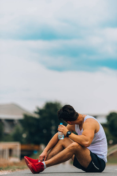 Fiatal férfi az ujjatlan gazdaságban fitness palack vízzel - Fotó, kép