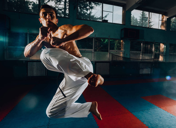 Hombre atlético pateando saco de boxeo con pierna, entrenamiento kickboxing
  - Foto, imagen
