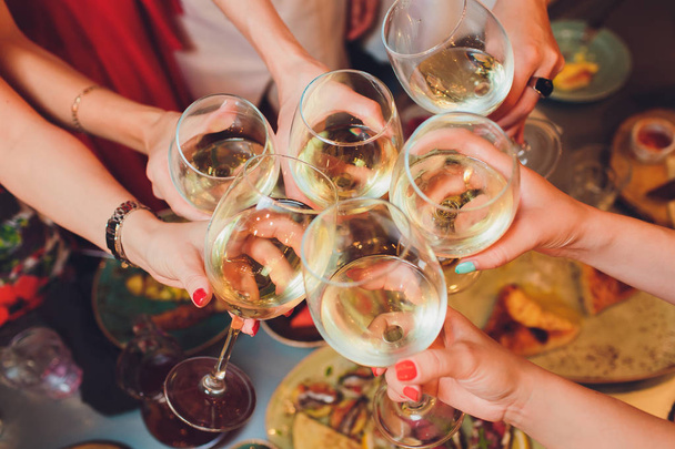 Menselijke handen met glazen rode wijn rammelende ze boven tafel geserveerd. - Foto, afbeelding