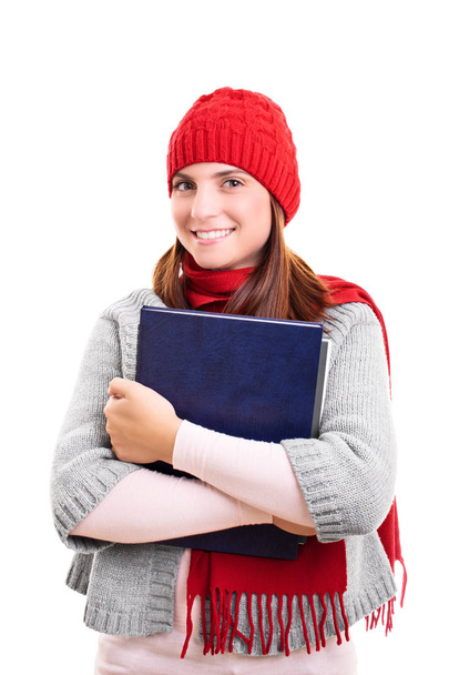 Smiling student in winter clothes holding a book - Foto, afbeelding