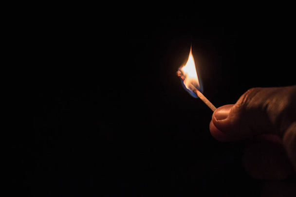 männliche Hand mit brennendem Streichholz beim Dimmen, das Licht ausschaltet - Foto, Bild