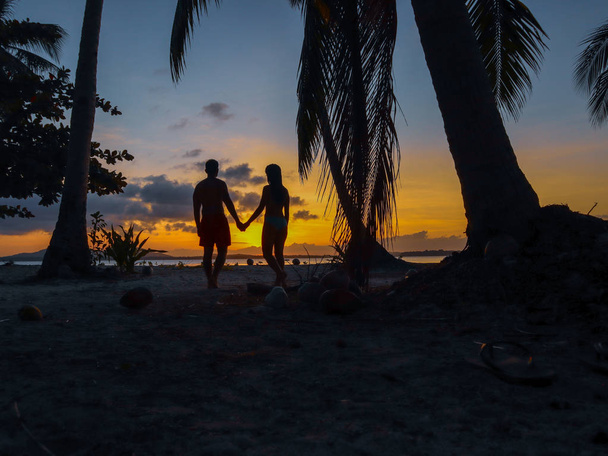 Encantador casal assistindo por do sol com palmeiras na ilha de Candaraman, em Balabac Filipinas
 - Foto, Imagem