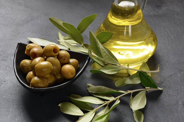 Extra virgin Olive oil , olive branch and olives on a dark background - Fotó, kép