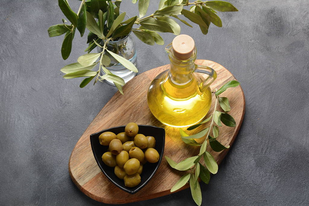 Extra virgin Olive oil , olive branch and olives on a dark background - Фото, изображение