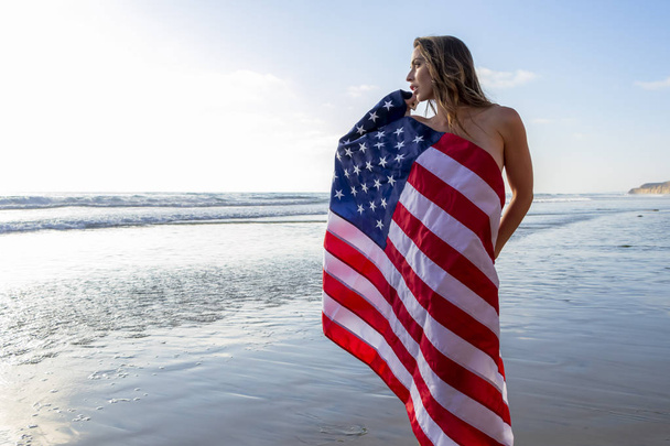 素敵なブルネットモデルは、アメリカ人と海岸でヌードポーズ - 写真・画像