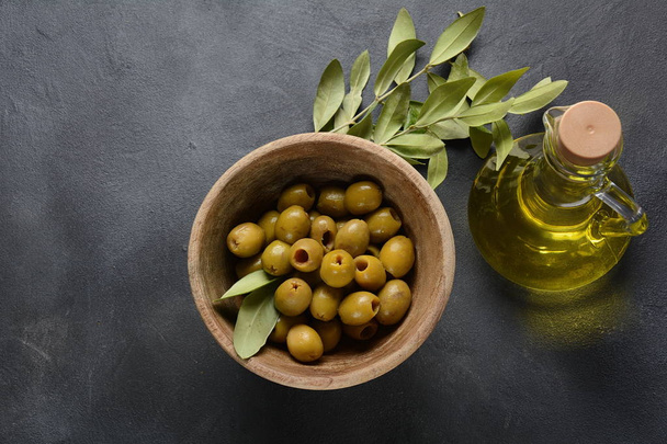 Extra virgin Olive oil , olive branch and olives on a dark background - Foto, afbeelding