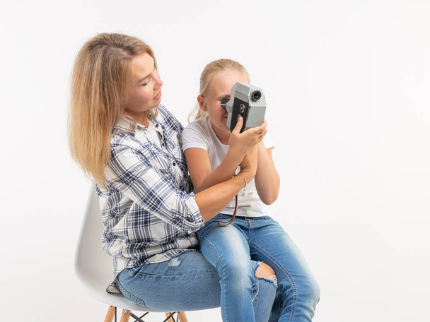 Technológiák, fényképezés és a család fogalma - anya és lánya retro fényképezőgép használata felett fehér háttér - Fotó, kép