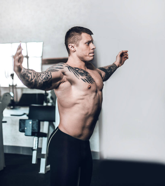 Seitenansicht. junger Bodybuilder posiert im Fitnessstudio - Foto, Bild