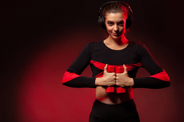 Sporty fit woman, athlete with dumbbells makes fitness exercising on red background. Fitness and workour motivation. - Foto, Imagen
