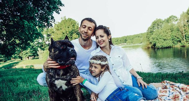 happy family with pet dog at picnic in a Sunny summer day. pregn - Zdjęcie, obraz