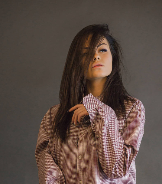 Vértes szépség pózol a szürke stúdió háttere kockás ing fiatal nő portréja - Fotó, kép
