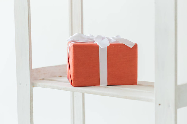 Święta i koncepcja urodzin-czerwone pudełko z białą wstążką stojącą na półce - Zdjęcie, obraz