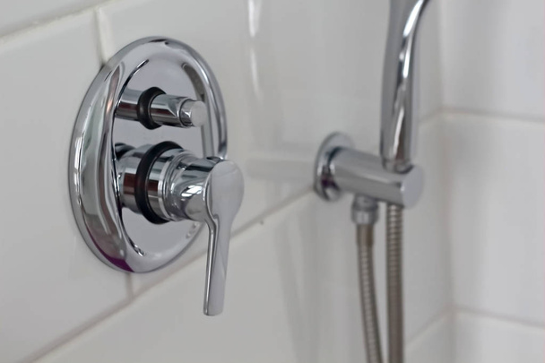 metallo argento lucido doccia rubinetto doccia irrigazione può interruttore dell'acqua nel bagno di casa dell'hotel con piastrelle bianche sulla parete. Bagno interno di lusso
  - Foto, immagini