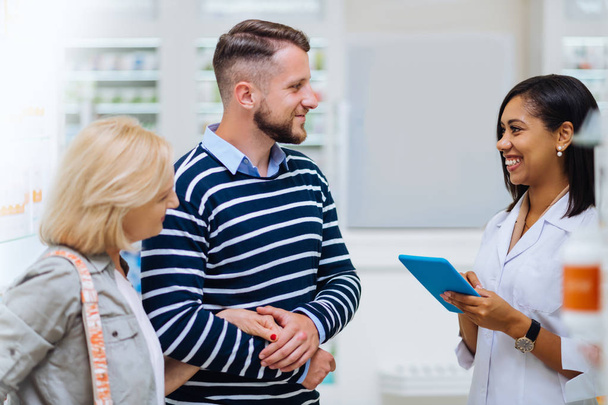 Kind brunette man consulting with pretty pharmacist - Photo, Image