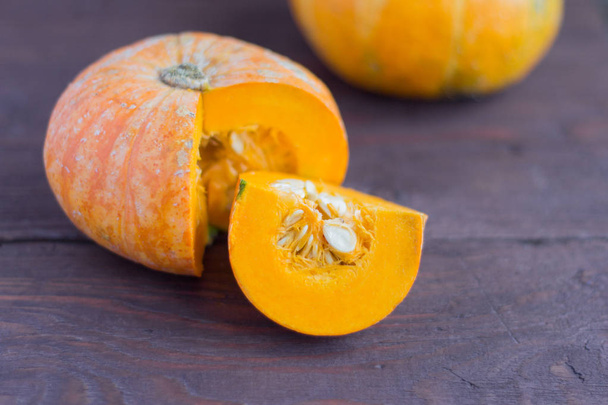 ripe fresh pumpkin cut into a wooden background,close-up - Photo, Image