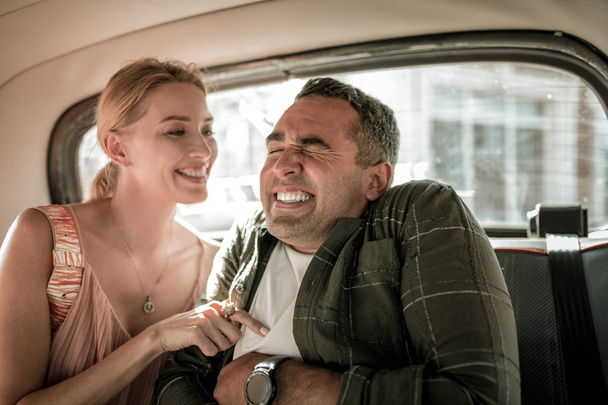 Husband and wife having fun tickling in the car. - Фото, изображение