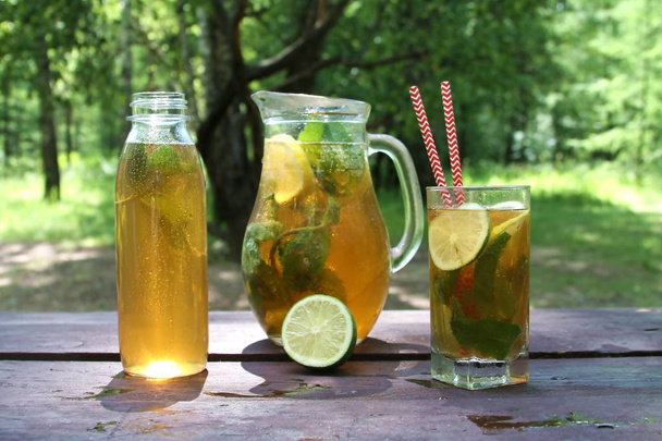 Kombucha chá fermentado Super alimentos em vidro, jarro e garrafa com hortelã e limão, Limão na mesa de madeira, ao ar livre
.  - Foto, Imagem