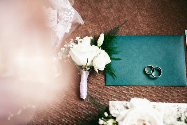 envelope convite em verde em um fundo escuro com um buquê de casamento e corrente de prata da noiva e anéis
 - Foto, Imagem