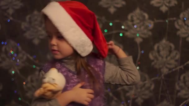 kleines Mädchen spielt mit Spielzeug neben Weihnachtsbaum. - Filmmaterial, Video