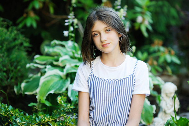 Beautiful smiling teenage girl in blue blouse, against green of summer park. - Fotografie, Obrázek