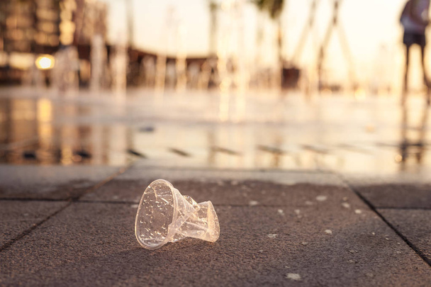 Plastic cup lying on pavement near dry fountain - Foto, imagen