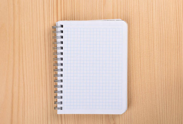 Squared paper notebook on wooden table top view. - Photo, Image