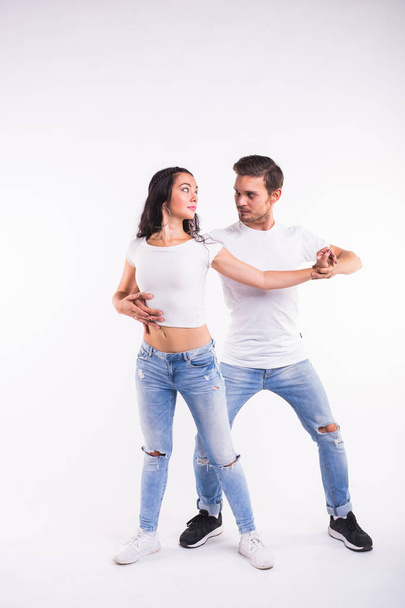 Jeune couple dansant danse sociale latine bachata, merengue, salsa. Deux pose d'élégance sur fond blanc
 - Photo, image
