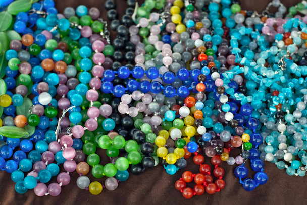 Necklace of colorful stones on the table. Many different jewelry and beads made of natural precious minerals. Stones jewelry is on sale at the fair. - Foto, afbeelding