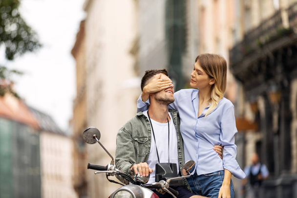 Happy couple of tourist travelers around city with motorbike scooter - Wander friends having fun on road trip in city - Travel concept with adult people on world tour - Warm filter - Фото, зображення