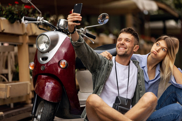 Happy couple on scooter making selfie photo on smartphone outdoors. People Travel On Weekend. High Resolution. - Foto, Imagem