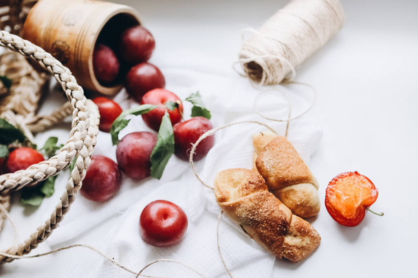Flatley of ripe plums and juicy croissants with sugar on a white background. View from above. - Foto, Imagen