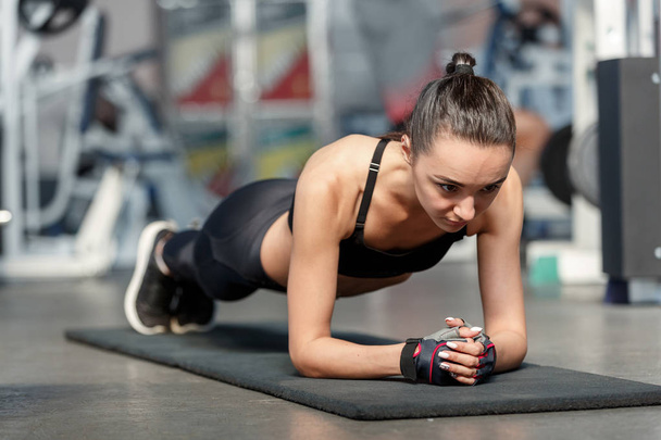 Jovem mulher esportiva fazendo exercício de prancha em um ginásio
 - Foto, Imagem