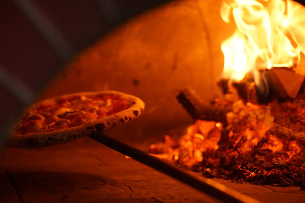 Cooking Neapolitan pizza in a wood-fired oven. - 写真・画像