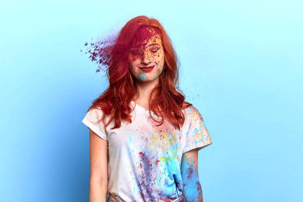 menina ruiva alegre sob explosão de pó colorido em cores Holi
 - Foto, Imagem