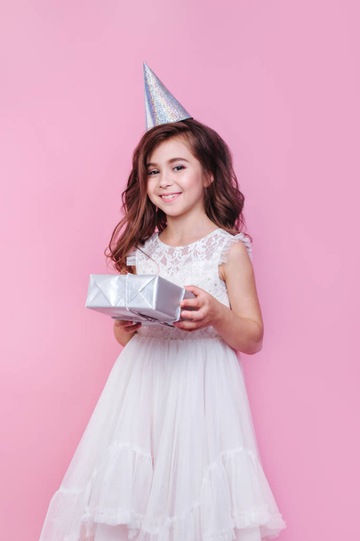 smiling child girl with gift box on birthday party on pink background - Photo, Image