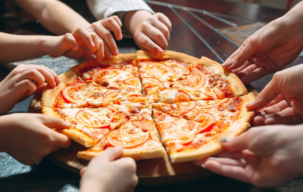 Hands taking pizza slices from wooden table, close up view. - Fotó, kép