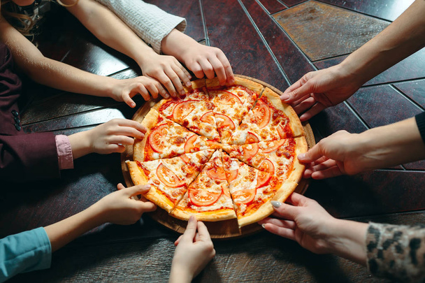 Hands taking pizza slices from wooden table, close up view. - Foto, Imagen