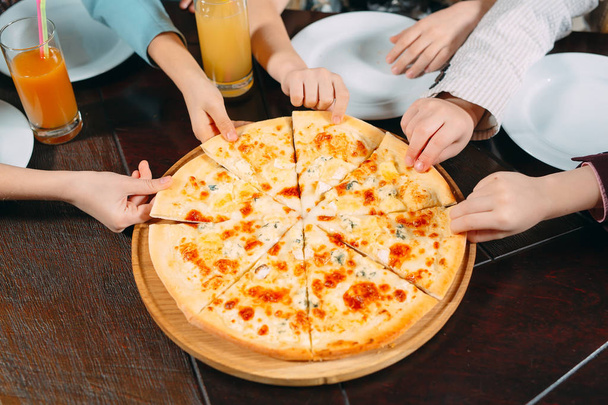 Hands taking pizza slices from wooden table, close up view. - Φωτογραφία, εικόνα