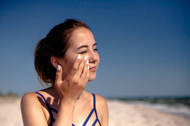 Девушка мажет солнцезащитный крем. На пляже используют солярий
. - Фото, изображение