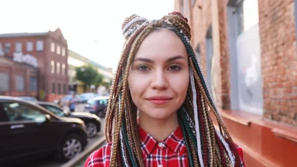Πορτρέτο του χαμογελαστή μοντέρνα έφηβο κορίτσι με ράμες σε αστικό φόντο, αργή κίνηση - Πλάνα, βίντεο