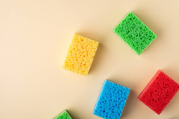 Yellow, green, red, blue sponges on cream colored paper background, copy space, top view, flat lay - Foto, Imagen