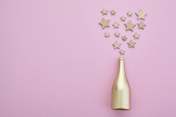 On a pink background a bottle of champagne and gold stars. Festive background. - Foto, Bild