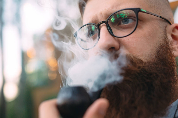 Portrait of man sitting and smoking pipe. - Фото, зображення