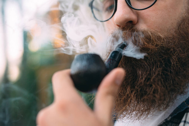 Portrait of man sitting and smoking pipe. - Fotografie, Obrázek